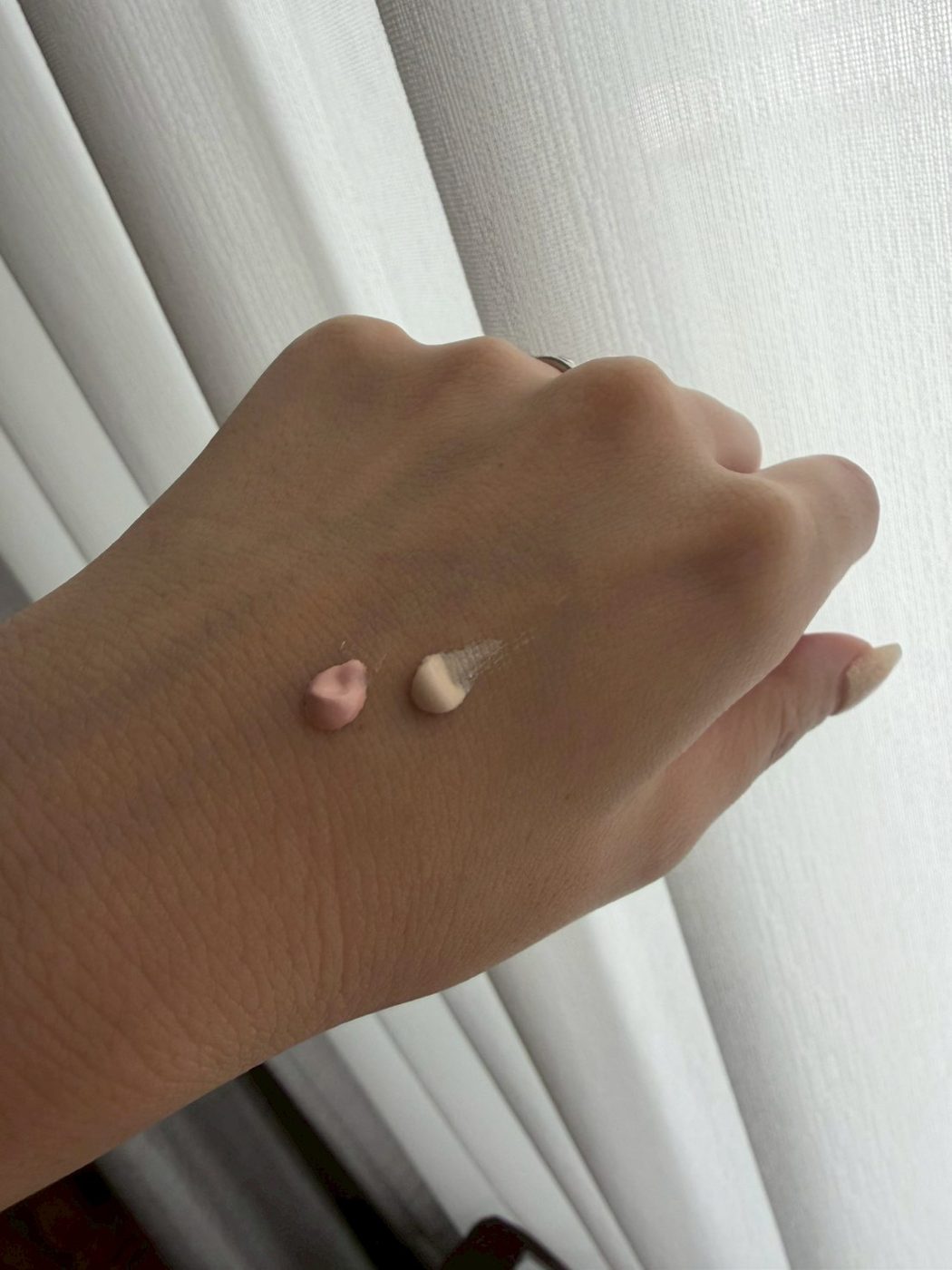 ALLIE Sunny Apricot (left) and Sheer Beige (right) sunscreen swatches on the back of a hand in natural light