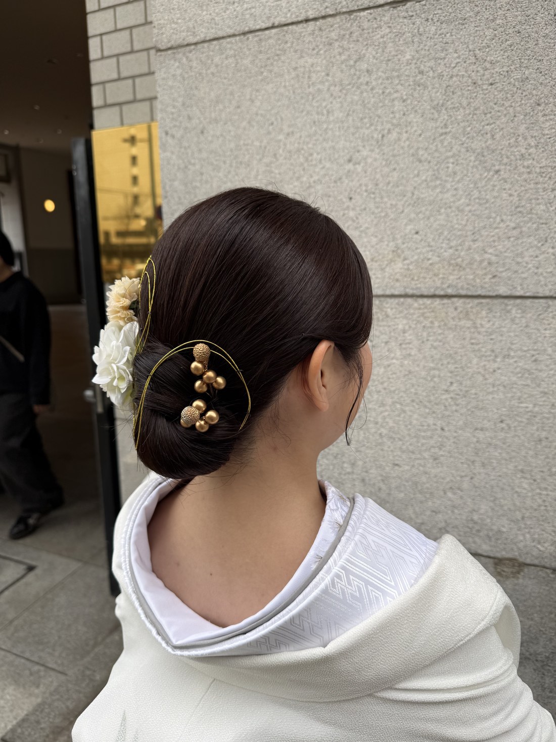 Bridal hairstyle with gold kanzashi and white flowers over a white wedding kimono