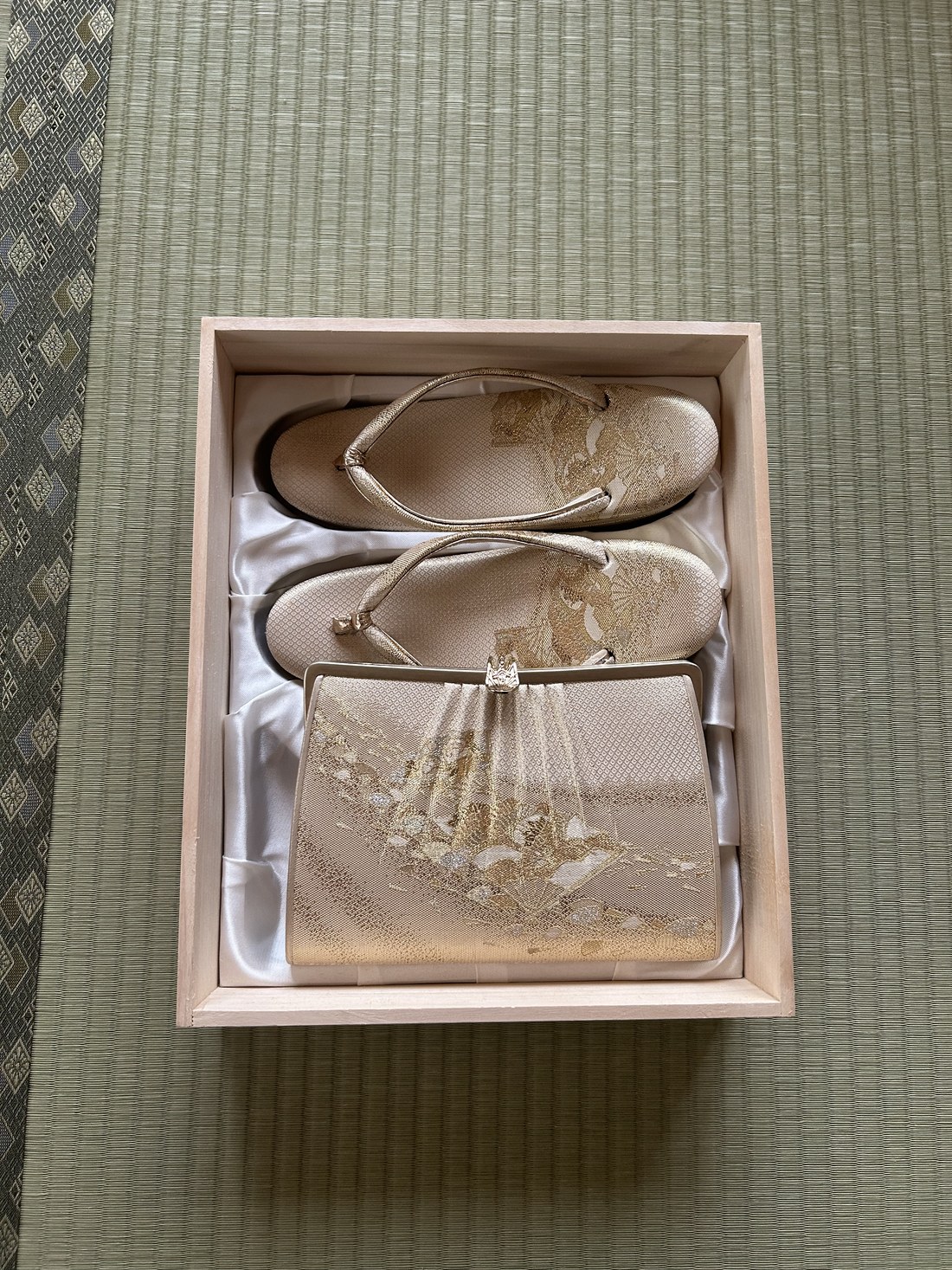 Gold bridal zori sandals and matching bag in a wooden box on tatami
