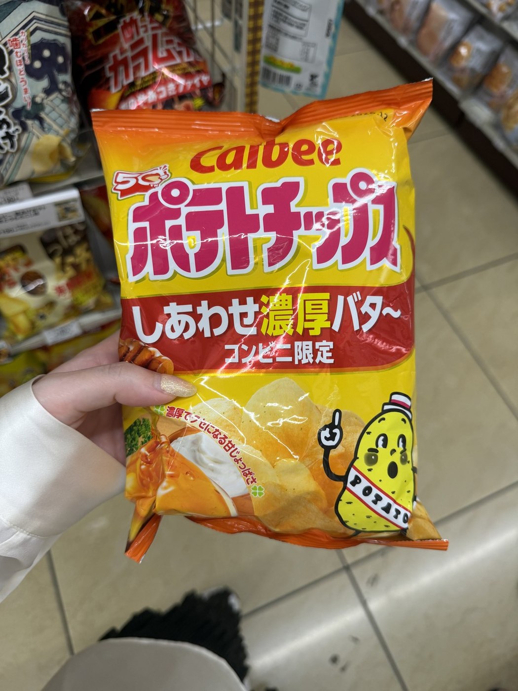 Hand holding a Calbee konbini-limited rich butter potato chip bag