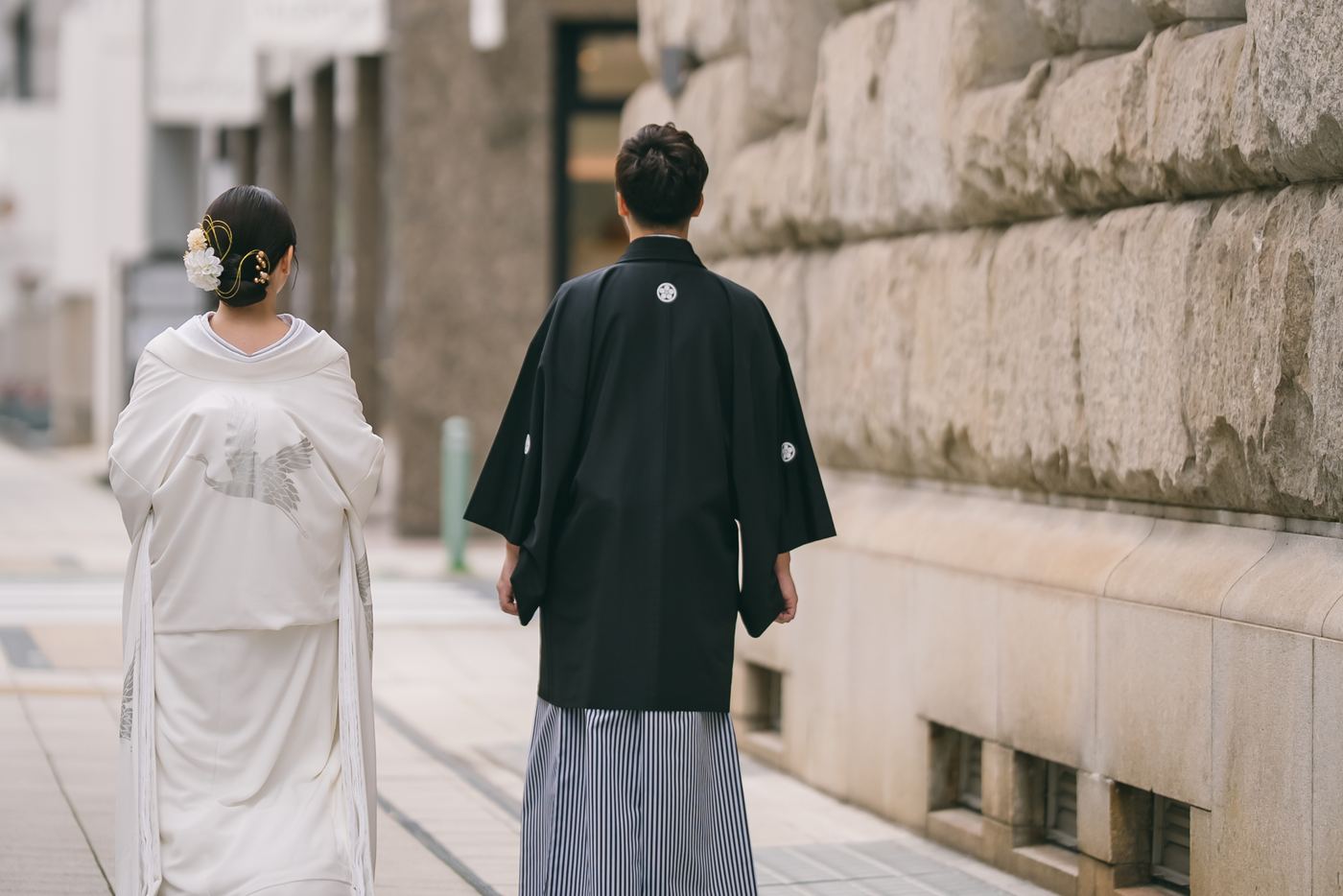 The two of us in kimono, walking ahead down a stone-paved street — follow us