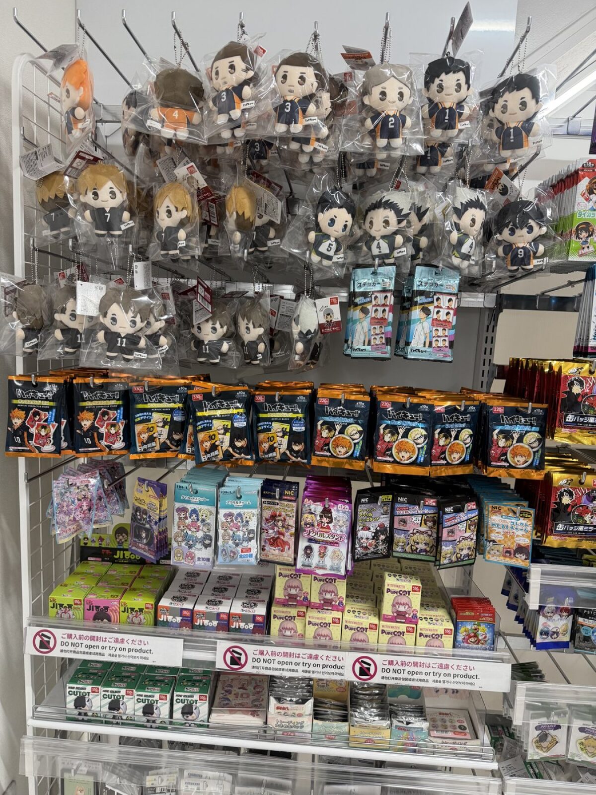 Anime character plush keychains and blind box goods on a DAISO shelf