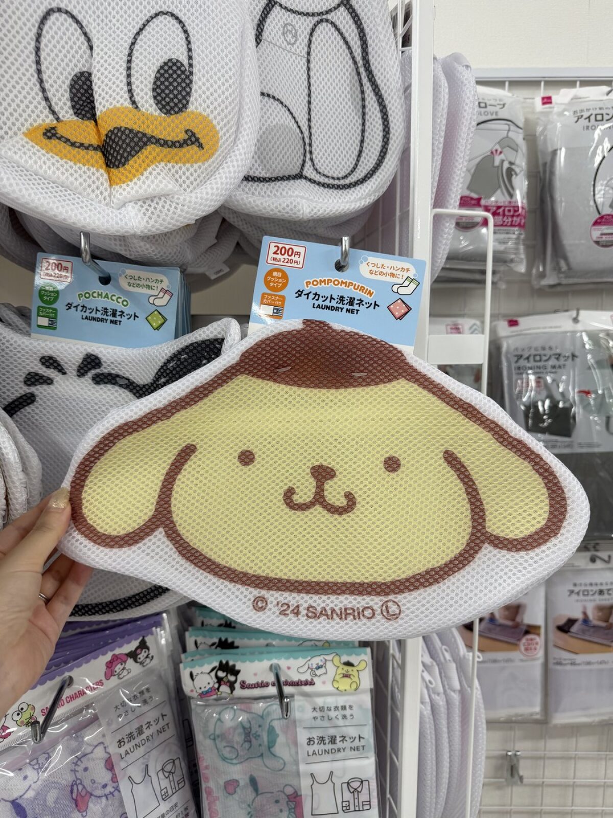 Pompompurin shaped laundry net held up in front of a DAISO shelf, priced 200 yen