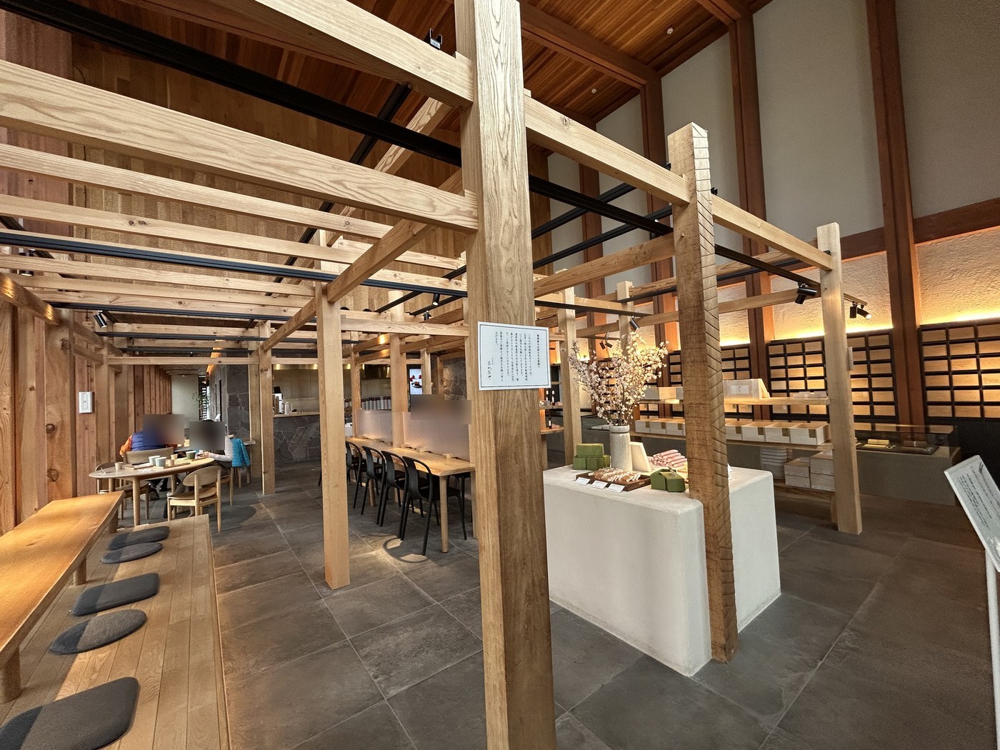 Warm wooden interior of the inarizushi shop with tall beams, shared tables and a sweets counter