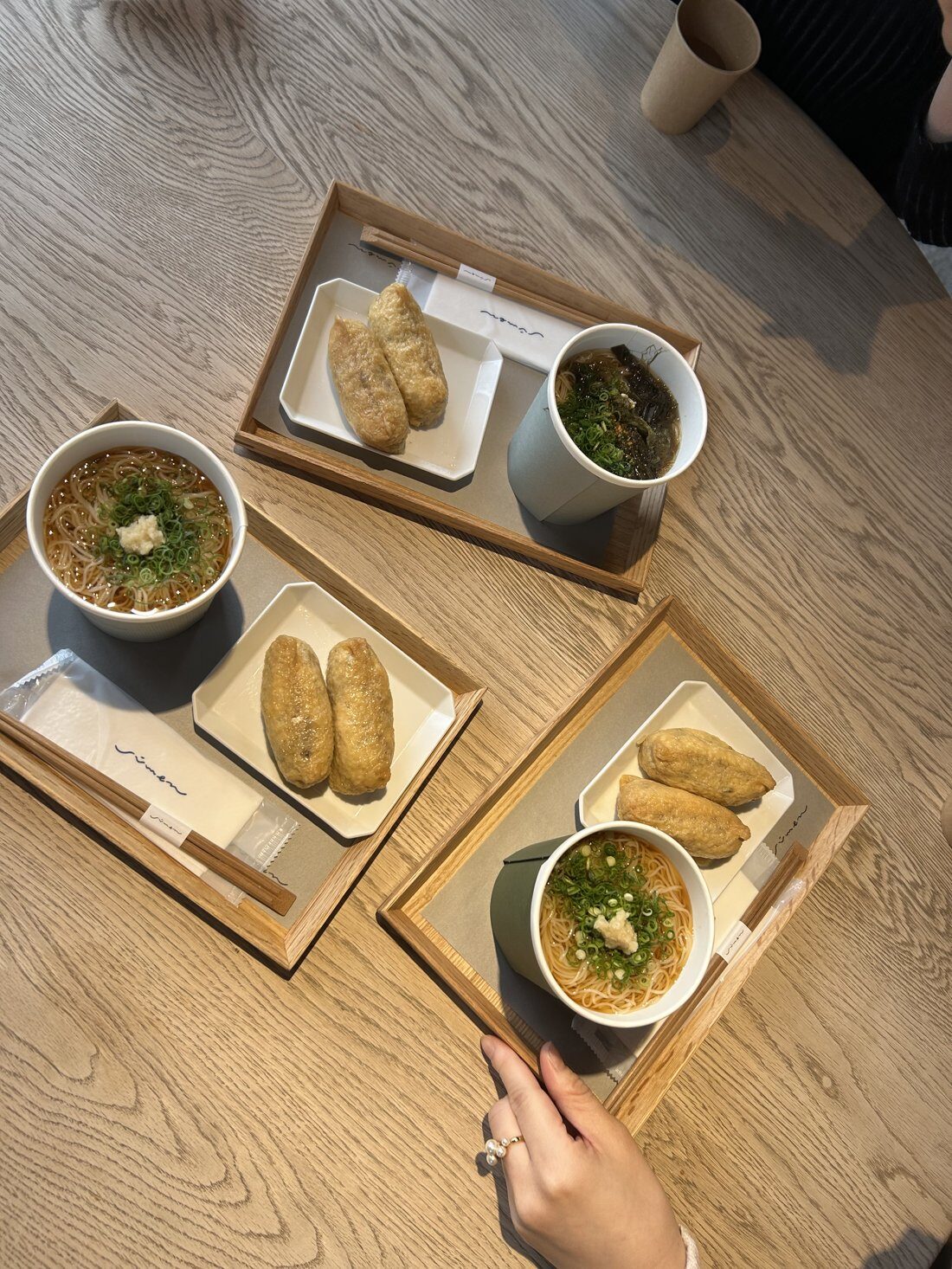 Two inarizushi lunch trays with soup bowls on a wooden table