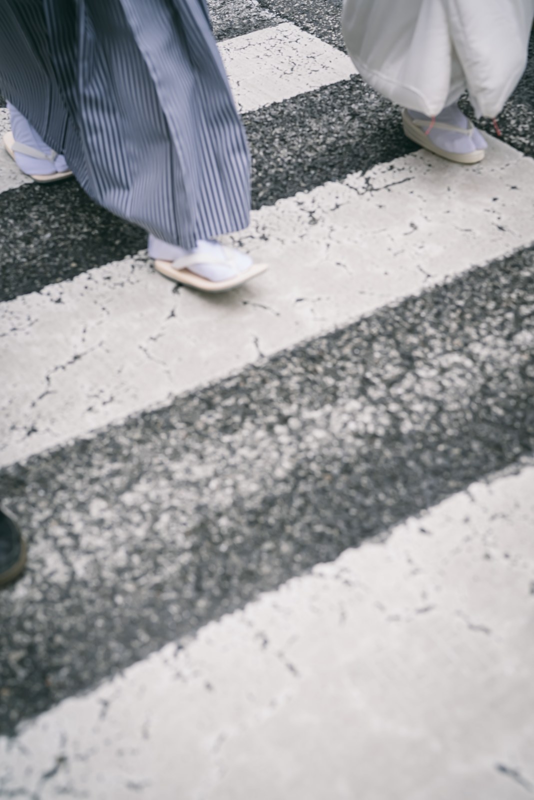 White zori sandals and tabi socks crossing a painted crosswalk in Kobe