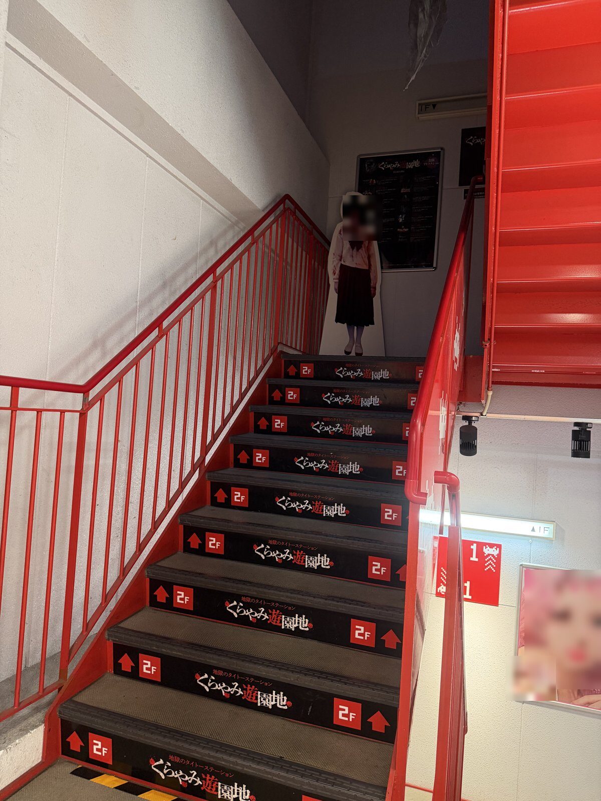 Red staircase of the Kurayami Yuenchi horror attraction in Osu with a ghost girl cutout at the top
