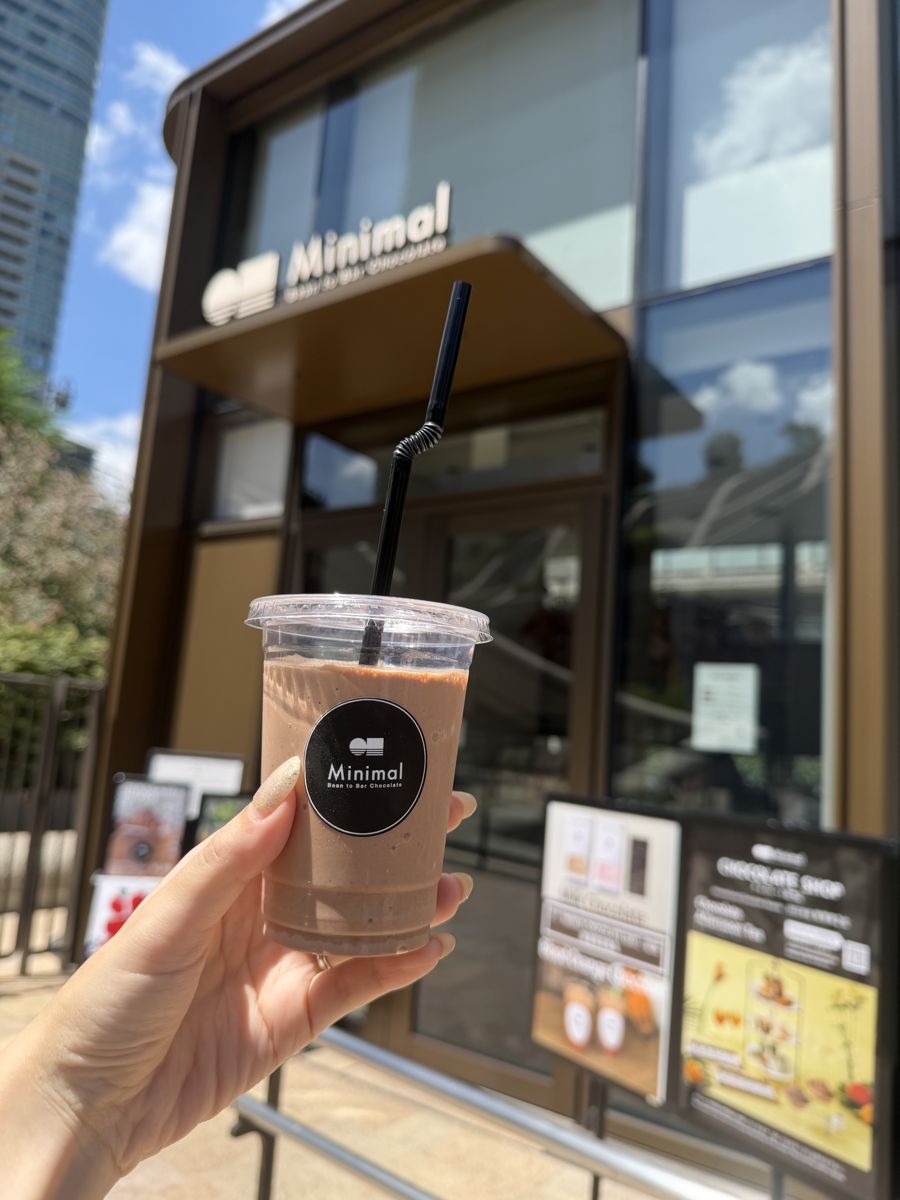 Hand holding iced chocolate drink outside Minimal bean to bar shop Tokyo