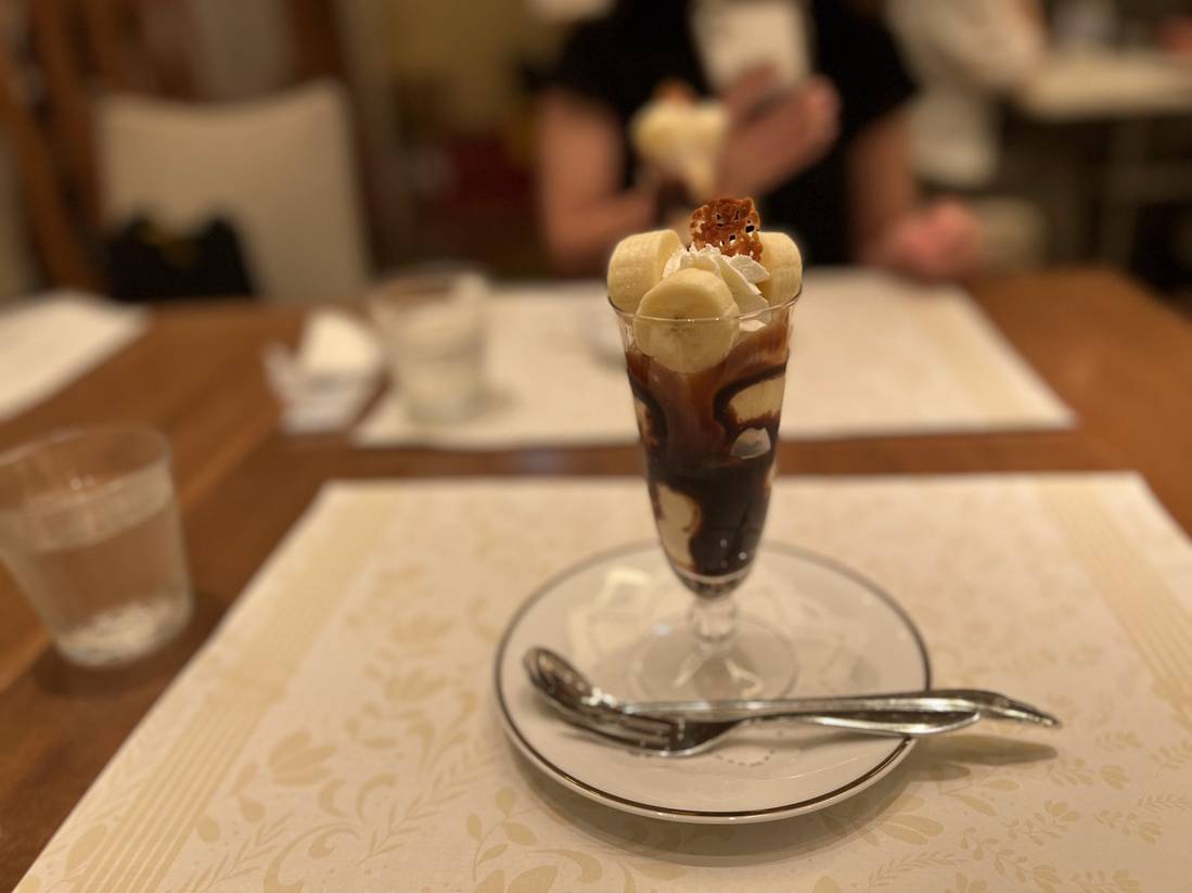 Banana parfait served with a long spoon and a doily