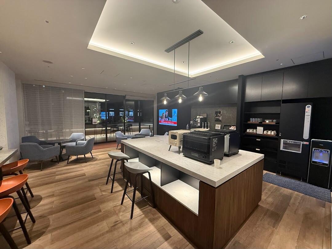 The shared lounge at Citadines Harbour Front Yokohama: kitchen island, toaster ovens, coffee machine and a few tables