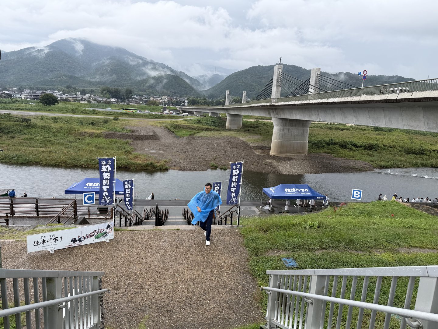 The Hozu River at Kameoka with mountains in low cloud and the boarding area signs