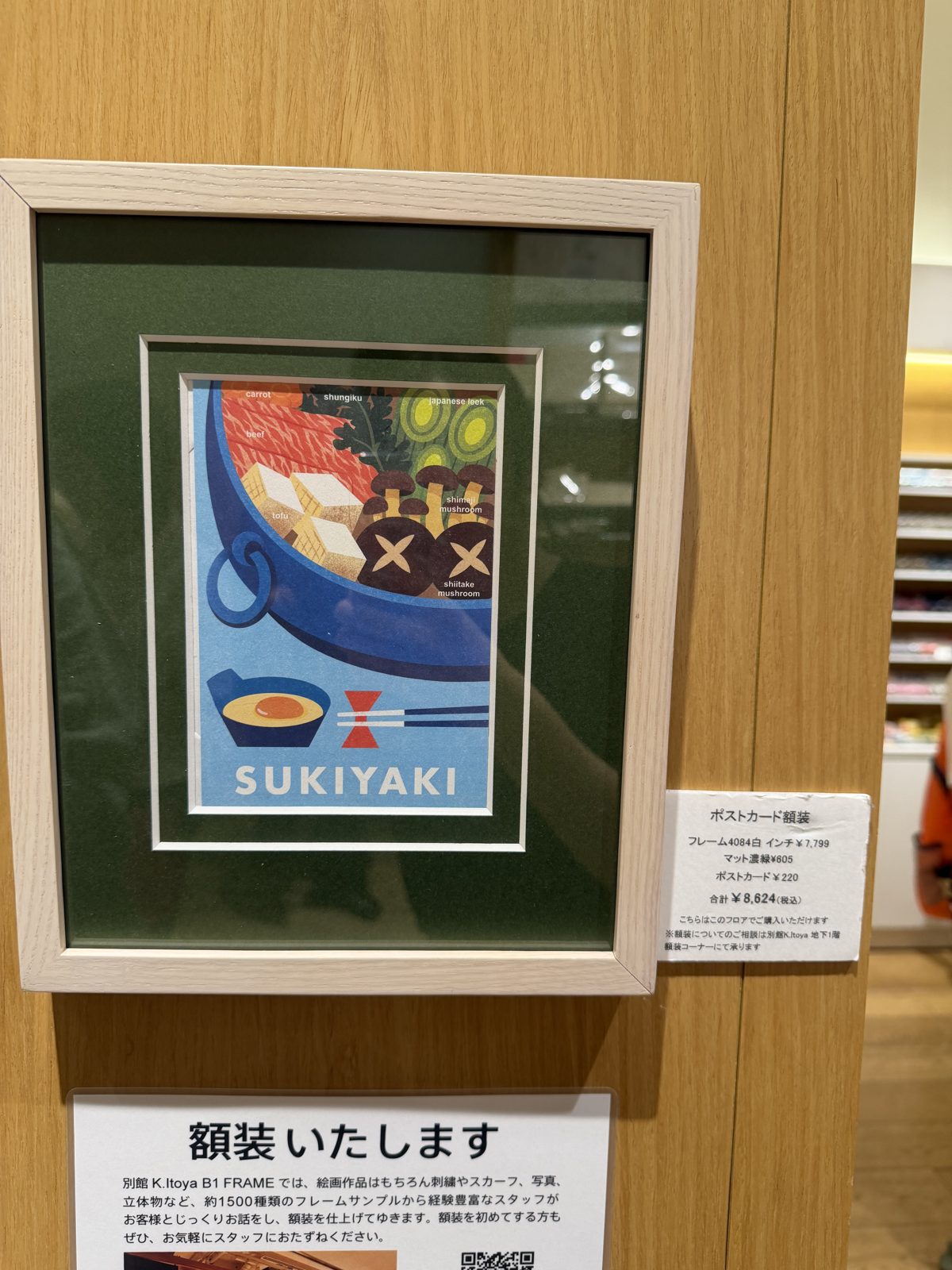 Framed Sukiyaki postcard at Ginza Itoya with a price breakdown sign, frame 7799 yen, mat 605 yen, postcard 220 yen, total 8624 yen tax included
