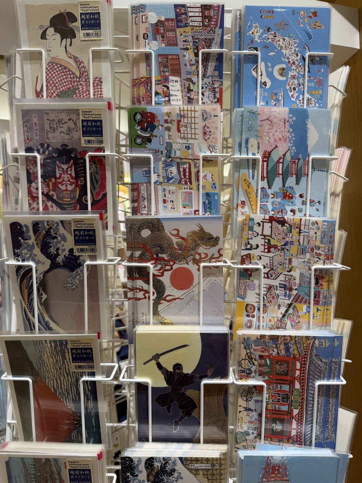 Postcard rack at Ginza Itoya with ukiyo-e prints, a ninja under the moon and Tokyo skyline cards