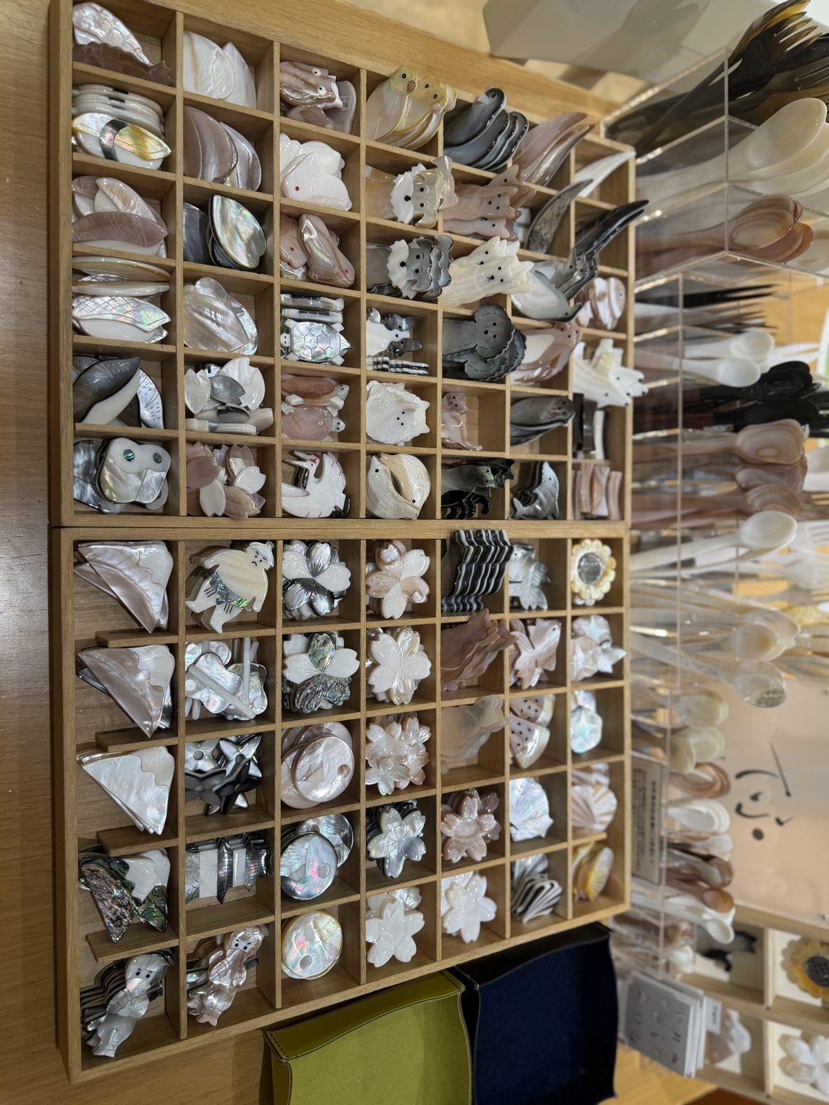Wooden drawer of small shell hair clips and brooches shaped like flowers and animals at Ginza Itoya