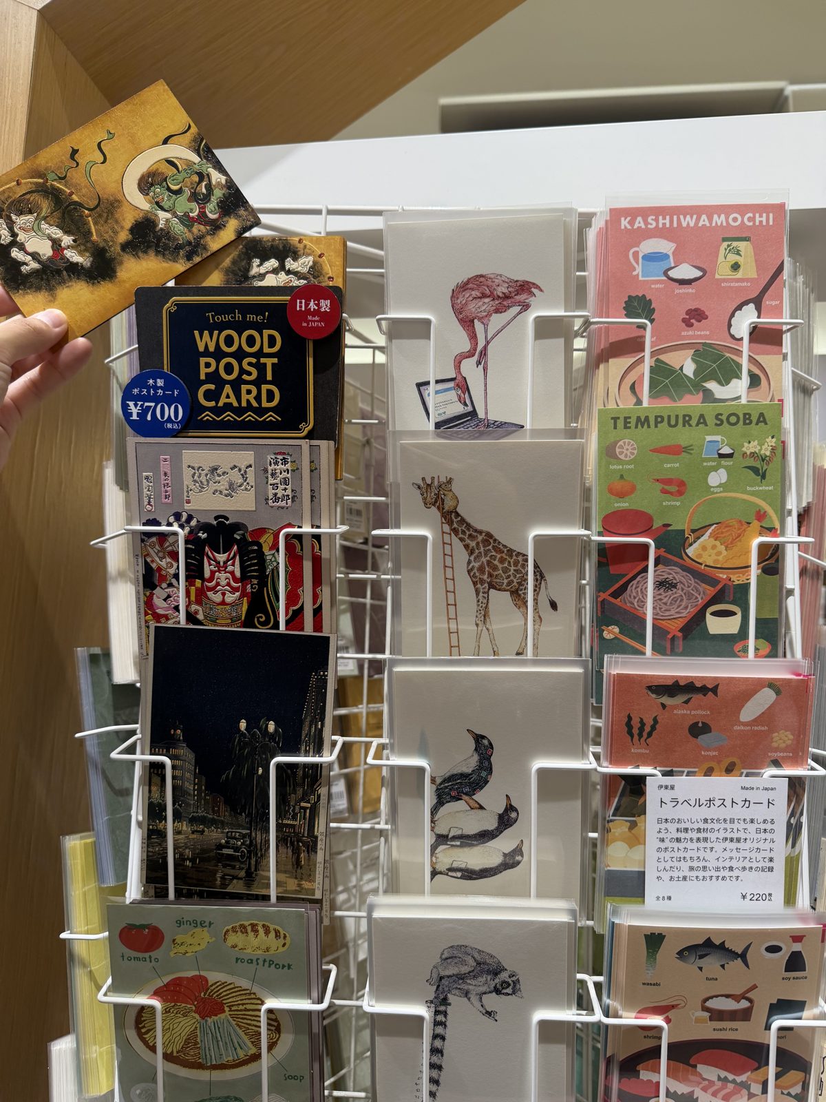 Wood postcard display at Ginza Itoya with a Touch me! Made in Japan sign and a 700 yen tax included sticker, beside illustrated Kashiwamochi and Tempura Soba recipe postcards