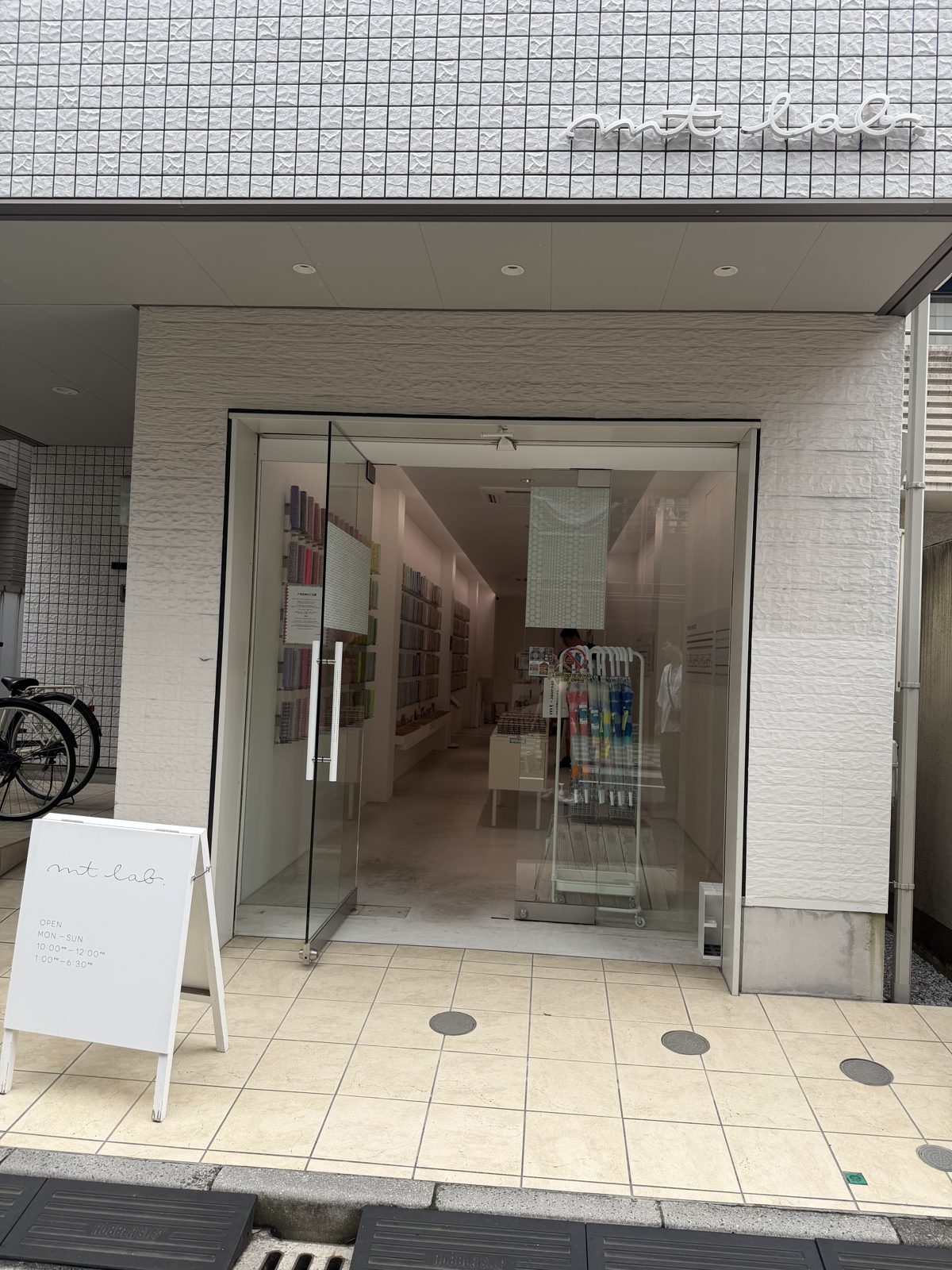 White tiled storefront of mt lab masking tape shop in Kuramae Tokyo with a glass door
