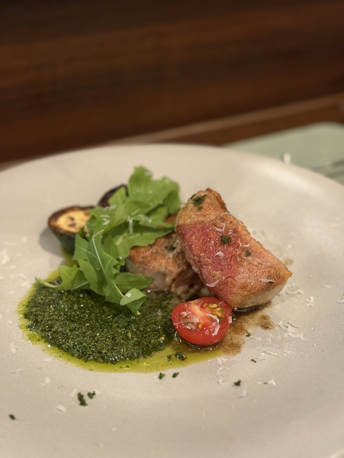 Pork fillet topped with ham, rocket, a cherry tomato and a green herb sauce