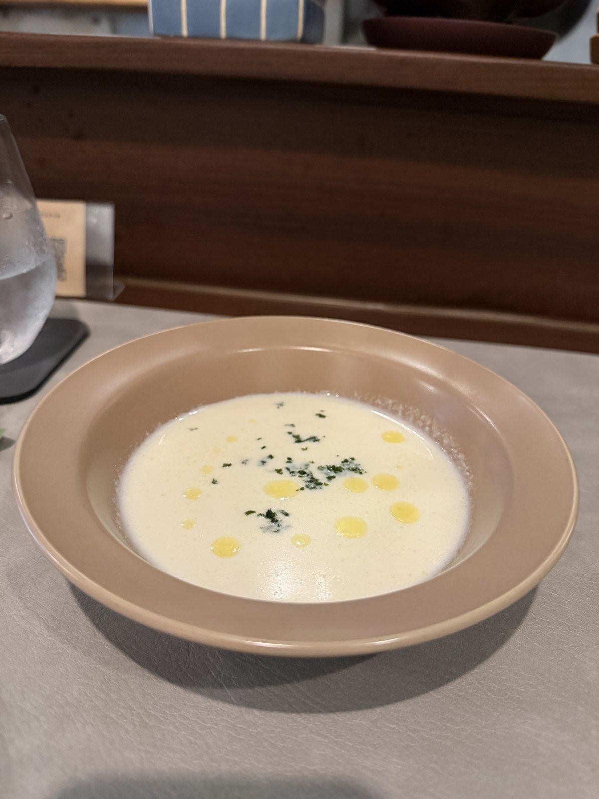 A bowl of creamy white soup with drops of olive oil