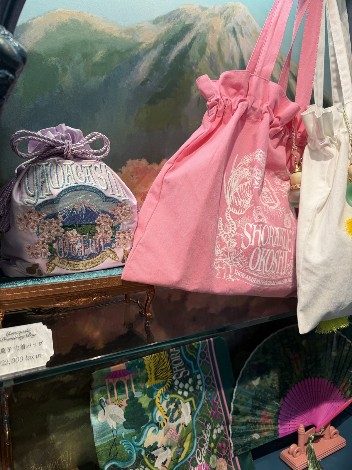 Embroidered drawstring bag and pink tote bags on display